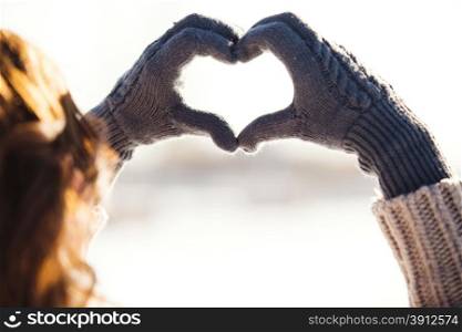 Young woman making heart symbol with hands, wintertime
