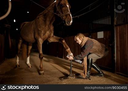 Young woman making horses hoof manicure, filing and shaping horseshoe. Stallion grooming and cleaning before riding. Young woman making horses hoof manicure, filing and shaping horseshoe