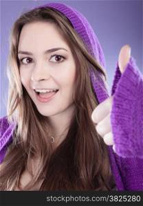 Young woman making showing thumb up sign hand gesture. Smiling happy girl celebrating success on violet