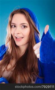 Young woman making showing thumb up sign hand gesture. Smiling happy girl celebrating success on blue