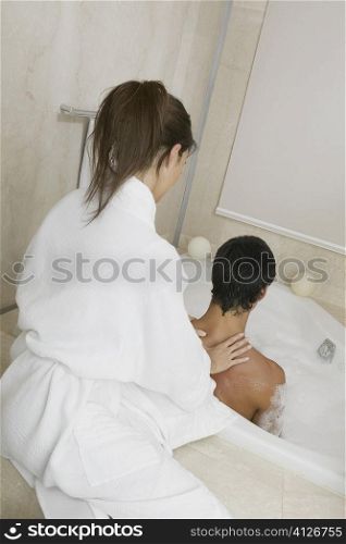 Young woman massaging a mid adult man&acute;s shoulders