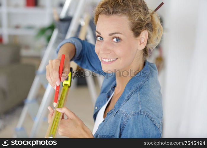 young woman measuring a wall with measuring tape
