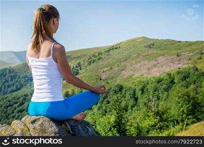 Young woman meditate on the top of mountain in sunrise time