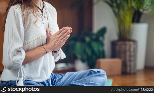 Young woman meditate while practicing yoga. Sitting in lotus pose with hands in prayer position.