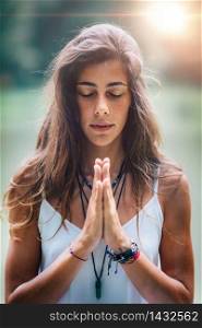 Young woman meditates, practicing yoga in nature. Hands in prayer position.