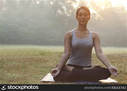 Young woman meditating in park