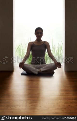 Young woman meditating on hardwood floor