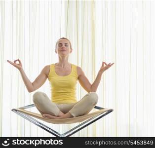 Young woman meditating on modern chair