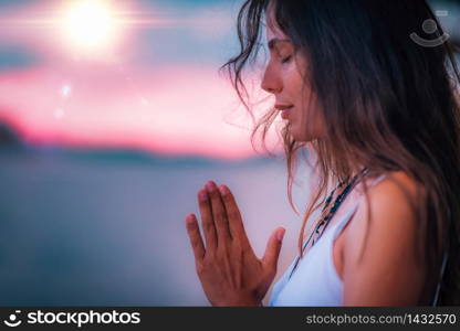 Young woman meditating with her eyes closed, practicing Yoga with hands in prayer position.