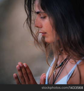 Young woman meditating with her eyes closed, practicing Yoga with hands in prayer position.