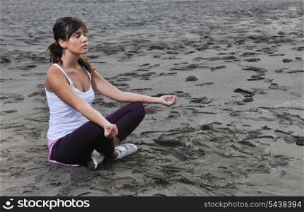 young woman meditating yoga in lotus positin on the beach at early morning
