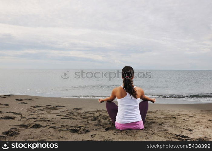 young woman meditating yoga in lotus positin on the beach at early morning