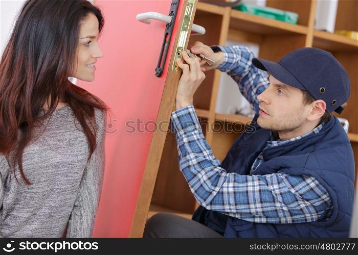 young woman meeting smiling service worker fixing her door