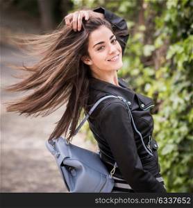 Young woman moving her hair in urban background wearing leather jacket