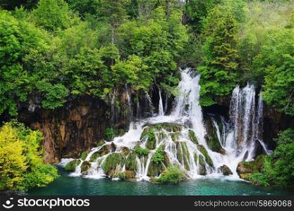 young woman near beautiful waterfalls on slopes of mountains