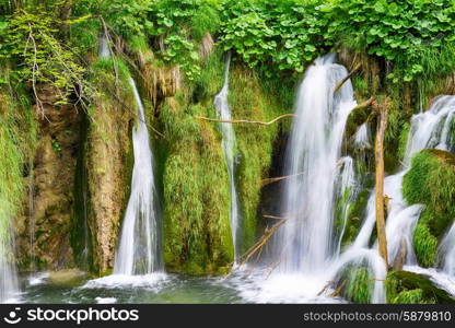 young woman near beautiful waterfalls on slopes of mountains