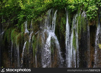 young woman near beautiful waterfalls on slopes of mountains