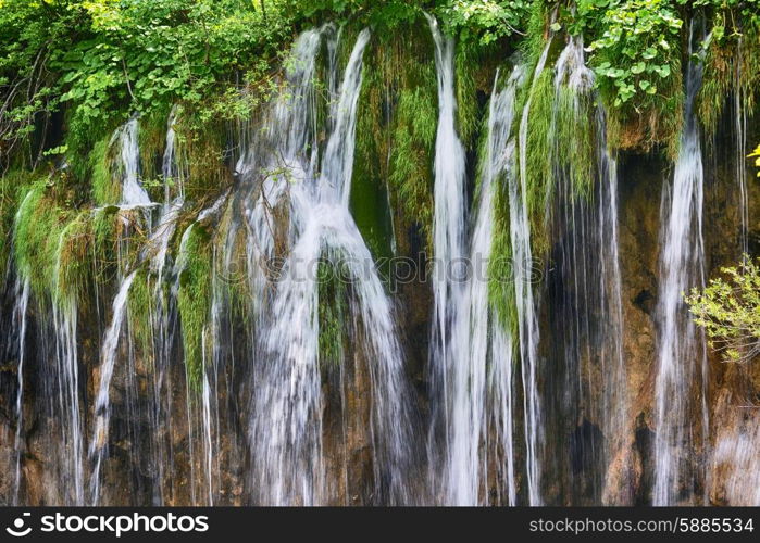 young woman near beautiful waterfalls on slopes of mountains