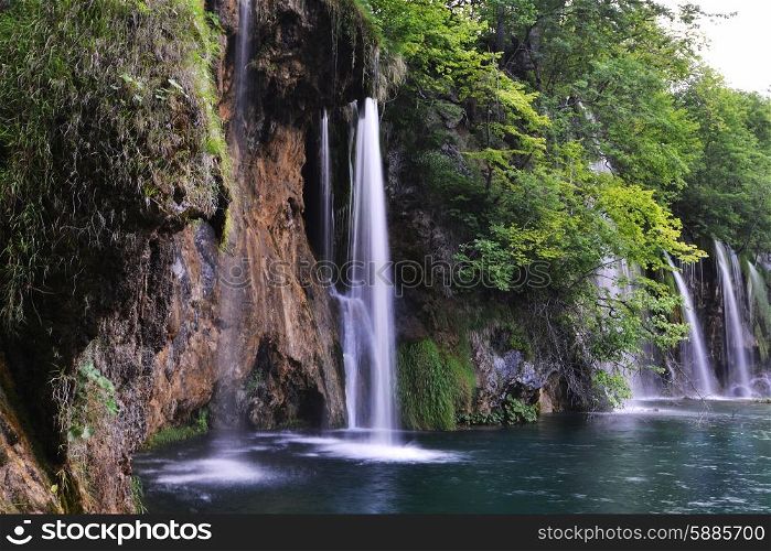 young woman near beautiful waterfalls on slopes of mountains