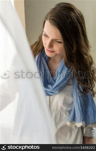 Young woman next to window looking down romantic pure portrait