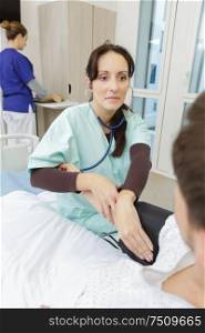 young woman nurse taking pulse of man