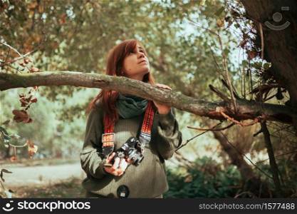 Young woman observing the forest with an old analog camera. Young woman observing the forest with an old camera