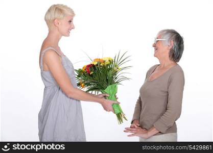 Young woman offering a bouquet of flowers to her grandmother