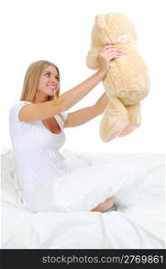Young woman on a bed in an embrace with teddybear. Isolated on white background