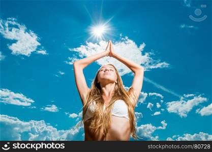 young woman on a blue sky background relaxes on a sunny day
