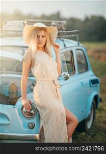 Young woman on a summer trip in a blue vintage car
