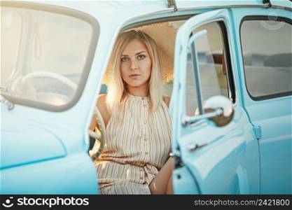 Young woman on a summer trip in a blue vintage car