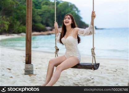 young woman on a wooden swing in the sea beach at Koh MunNork Island, Rayong, Thailand