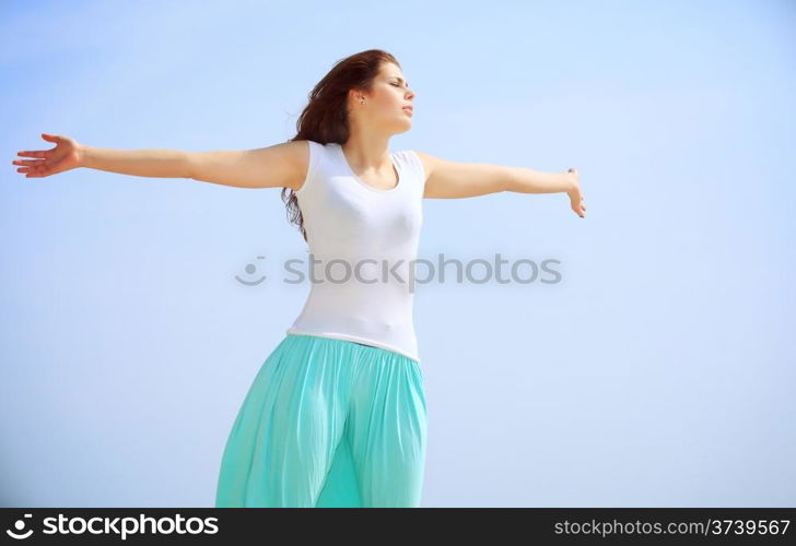 young woman on beach with raised hands looking to a sun, enjoying summer holiday