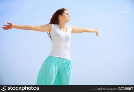 young woman on beach with raised hands looking to a sun, enjoying summer holiday