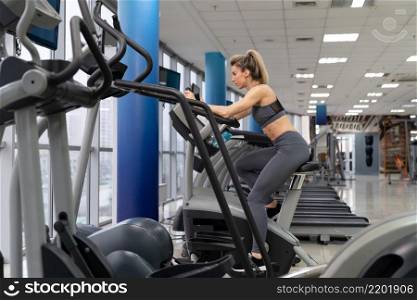 Young woman on bike at gym, exercising inside fitness center. Young woman on bike at gym exercising