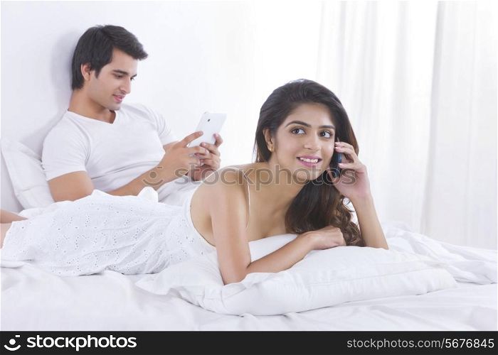 Young woman on call with man using digital tablet in bedroom