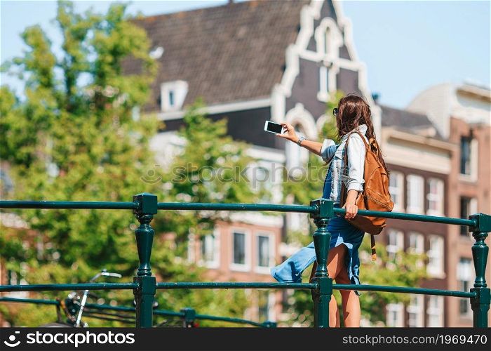 Young woman on european vacation in Amsterdam at the bridge take a photo. Happy young woman in european city