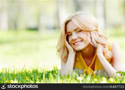 Young woman on grass. Smilng happy young woman lying on green grass meadow