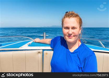 Young woman on head of a boat or yacht with blue sea