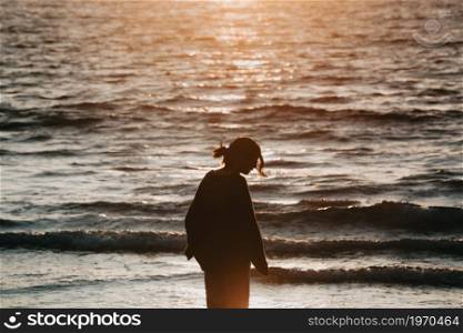 Young woman on spring clothes at the beach during a sunset