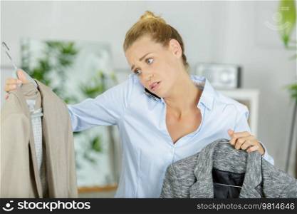 young woman on telephone choosing between two jackets