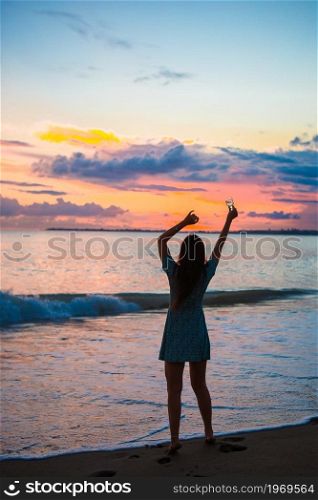 Young woman on the beach at sunset. Woman on the beach enjoying summer holidays looking at the sea