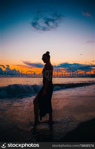 Young woman on the beach at sunset. Woman on the beach enjoying summer holidays looking at the sea