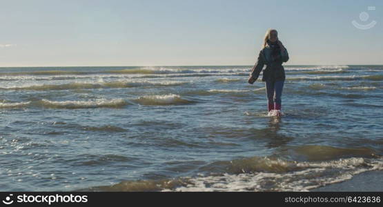 Young woman on the beach. The girl enjoying the warm autumn day. Portrait of beautiful girl near the water