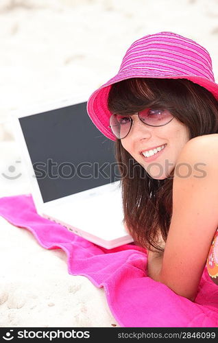 young woman on the beach with laptop