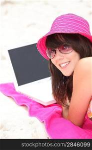 young woman on the beach with laptop