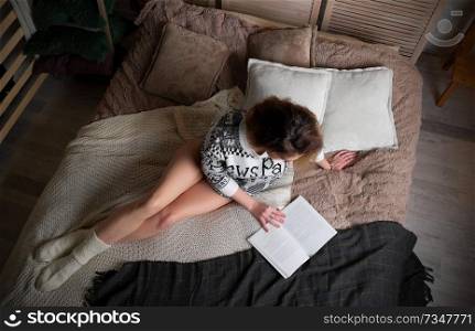 Young woman on the bed with book