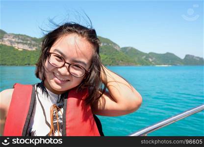 Young woman on the boat. Cute young woman with eyeglasses smiling happily on the boat while cruising the beautiful natural of the blue sea and sky in summer at Mu Ko Ang Thong National Park, Surat Thani, Thailand