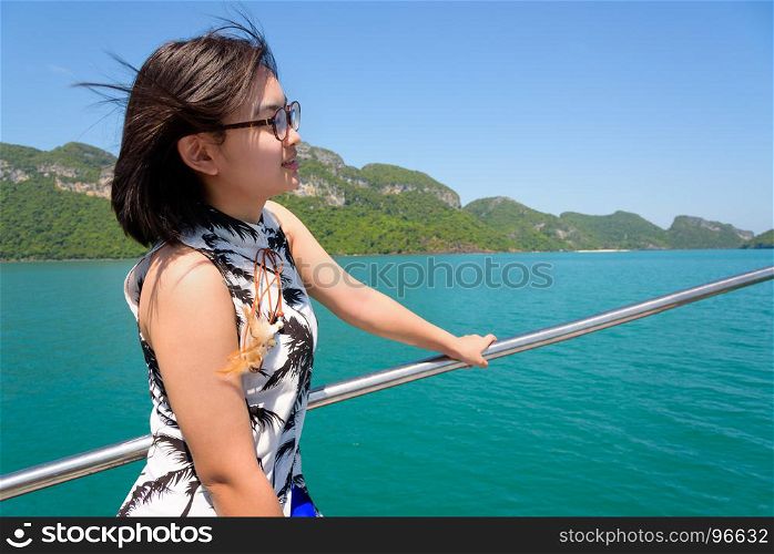 Young woman on the boat. Cute young woman with eyeglasses smiling happily on the boat while cruising the beautiful natural of the blue sea and sky in summer at Mu Ko Ang Thong National Park, Surat Thani, Thailand
