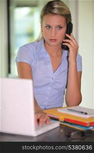 Young woman on the phone, in front of laptop